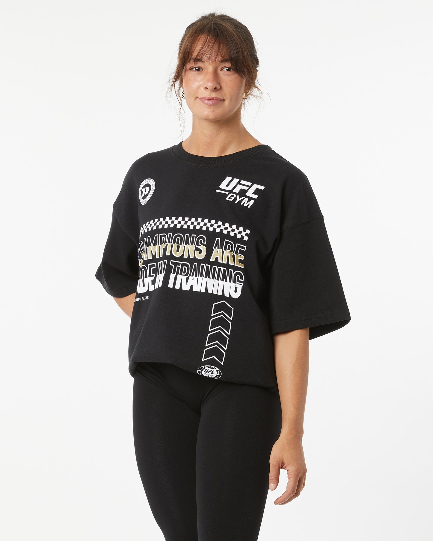 Woman wearing a black UFC Gym t-shirt on a white background facing forward