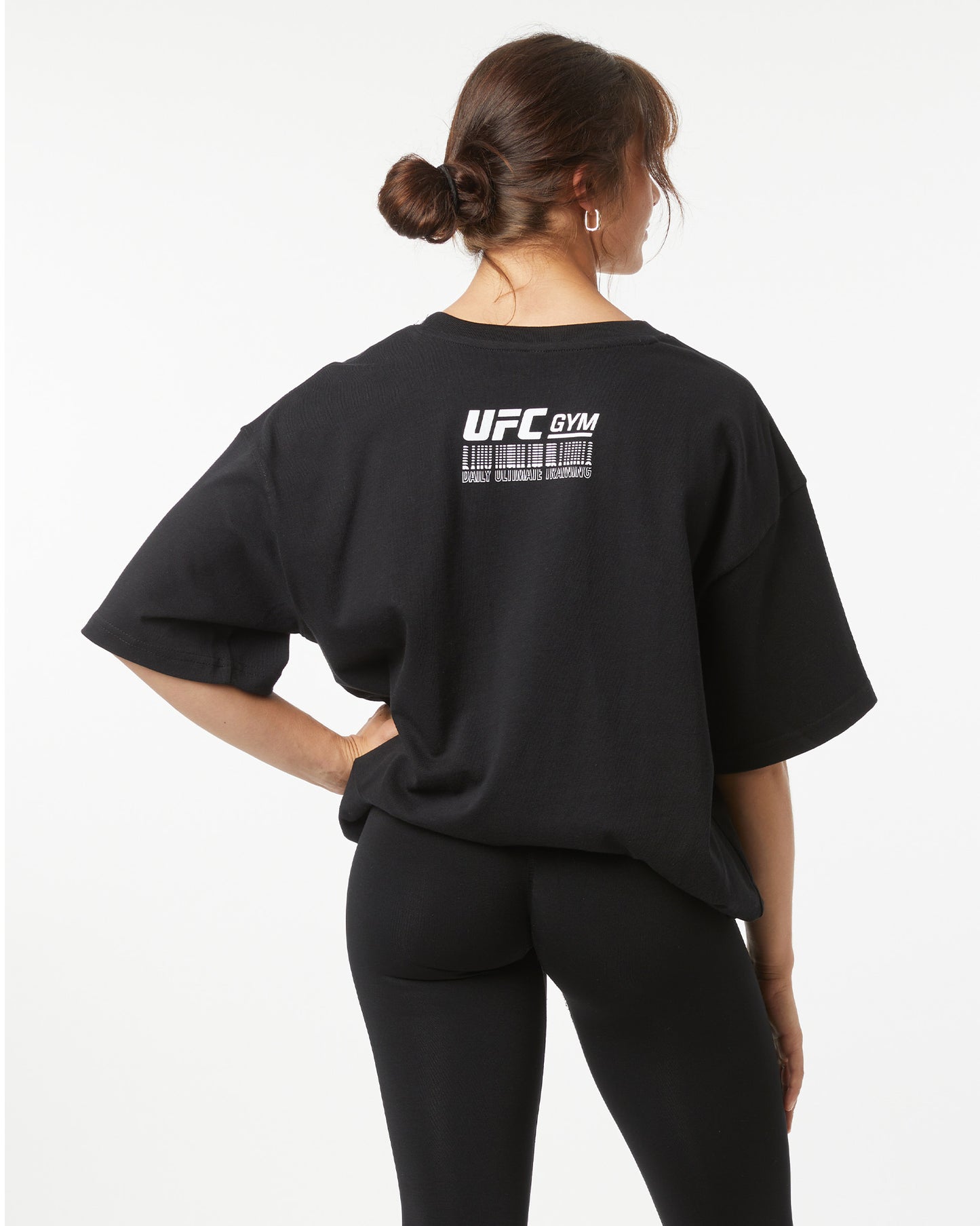 Person wearing a black 'UFC Gym' t-shirt on a white background turned around showing back logo on the shirt