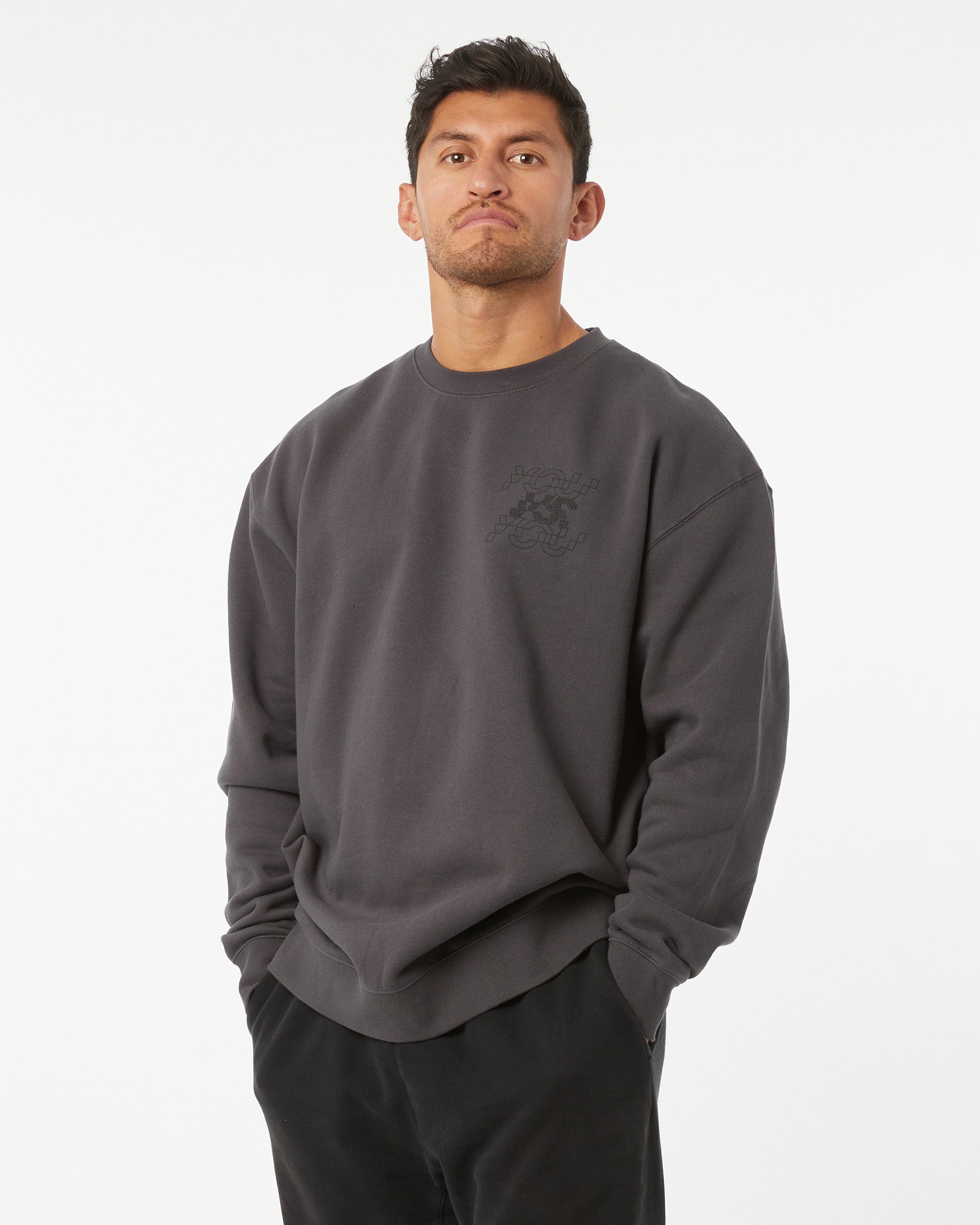 Man wearing a dark gray sweatshirt with a logo on a white background