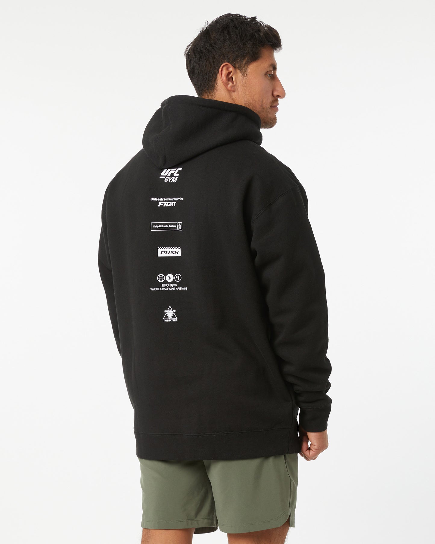 Person wearing a black hoodie with UFC branding on the back, standing against a white background looking right