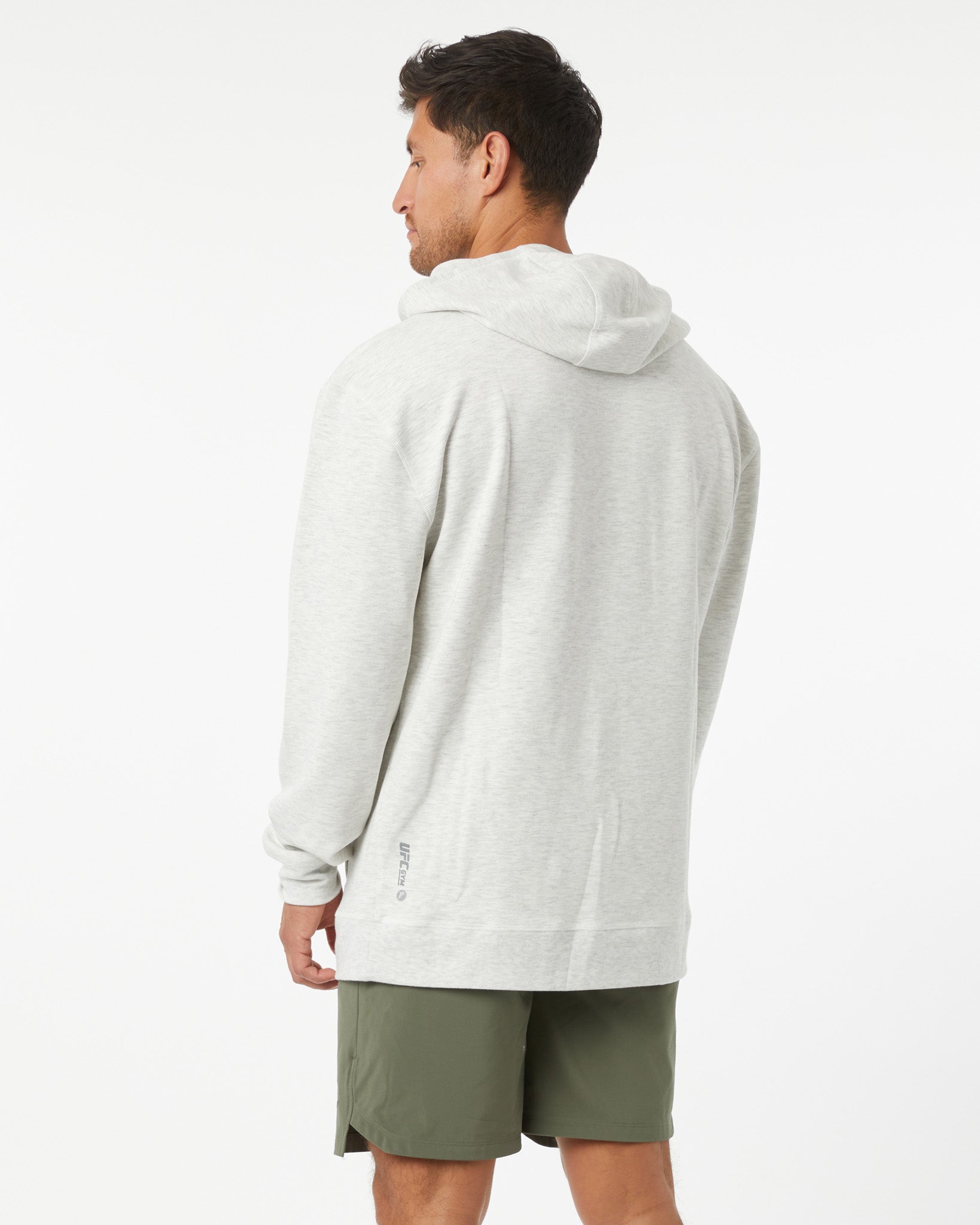 Man wearing a heather grey hoodie and green shorts on a white background