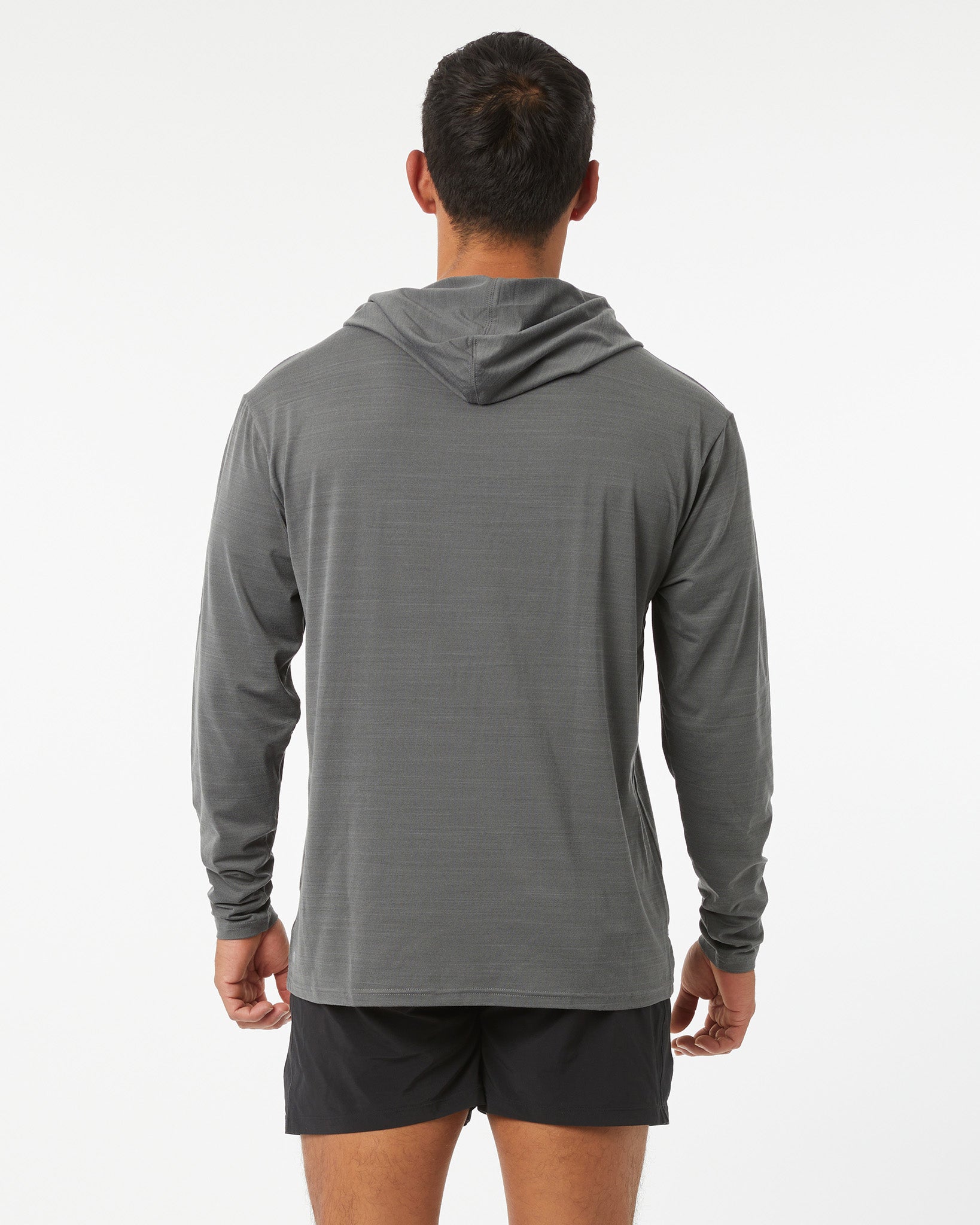 Person wearing a gray long-sleeve hoodie and black shorts on a white background