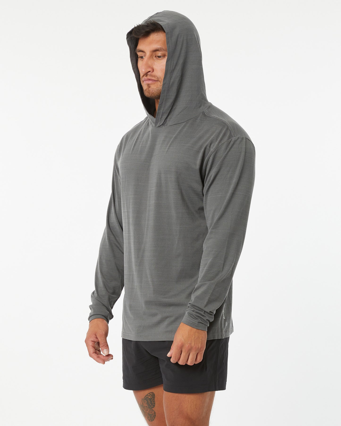 Man wearing a gray hooded long-sleeve shirt and black shorts on a white background