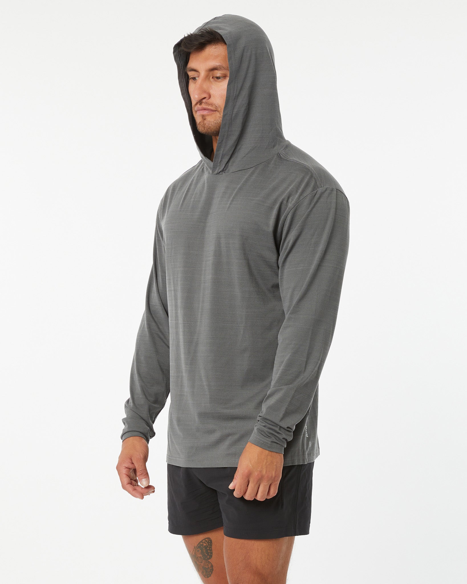 Man wearing a gray hooded long-sleeve shirt and black shorts on a white background
