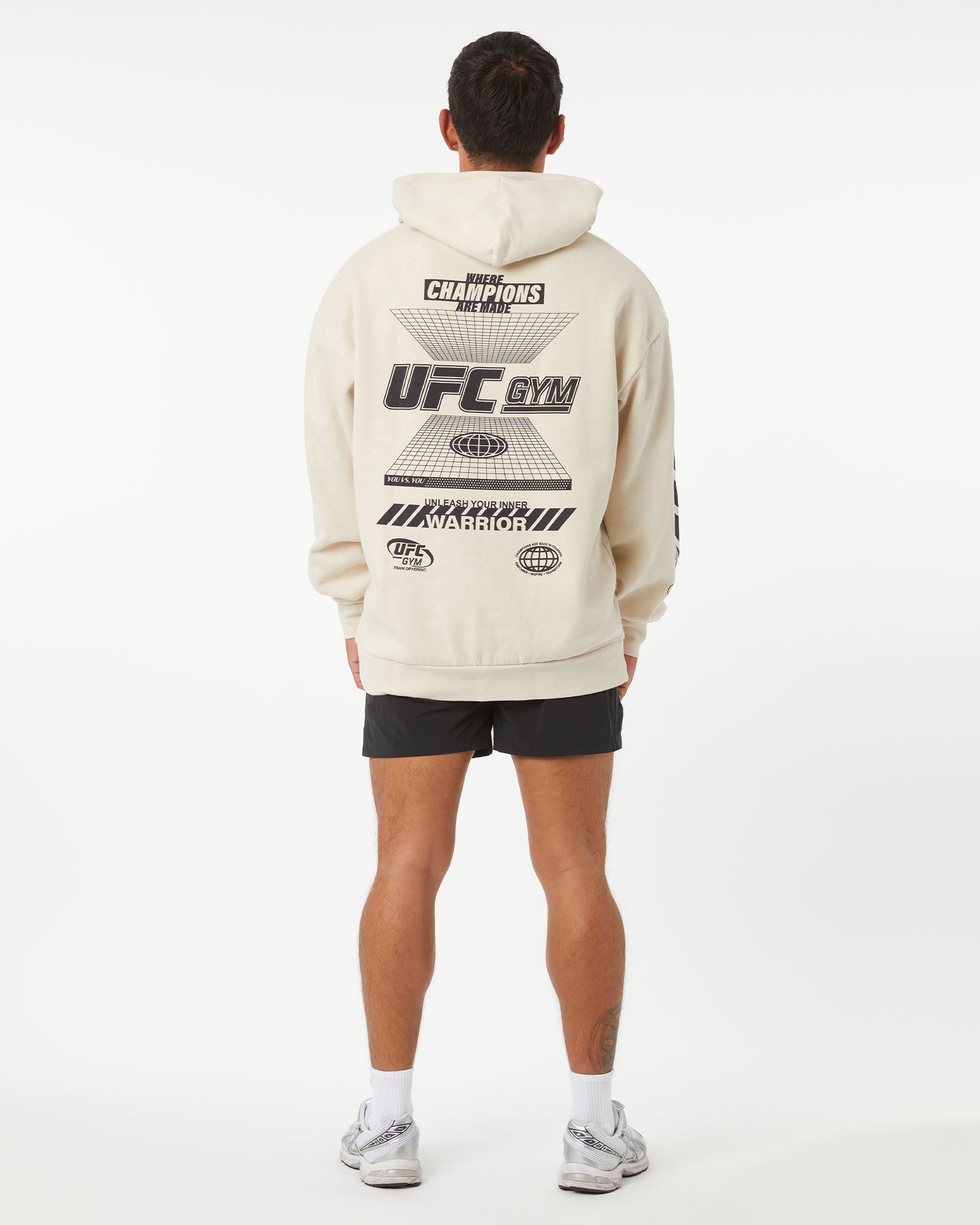 Person wearing a beige UFC Gym hoodie with branding on the back against a white background