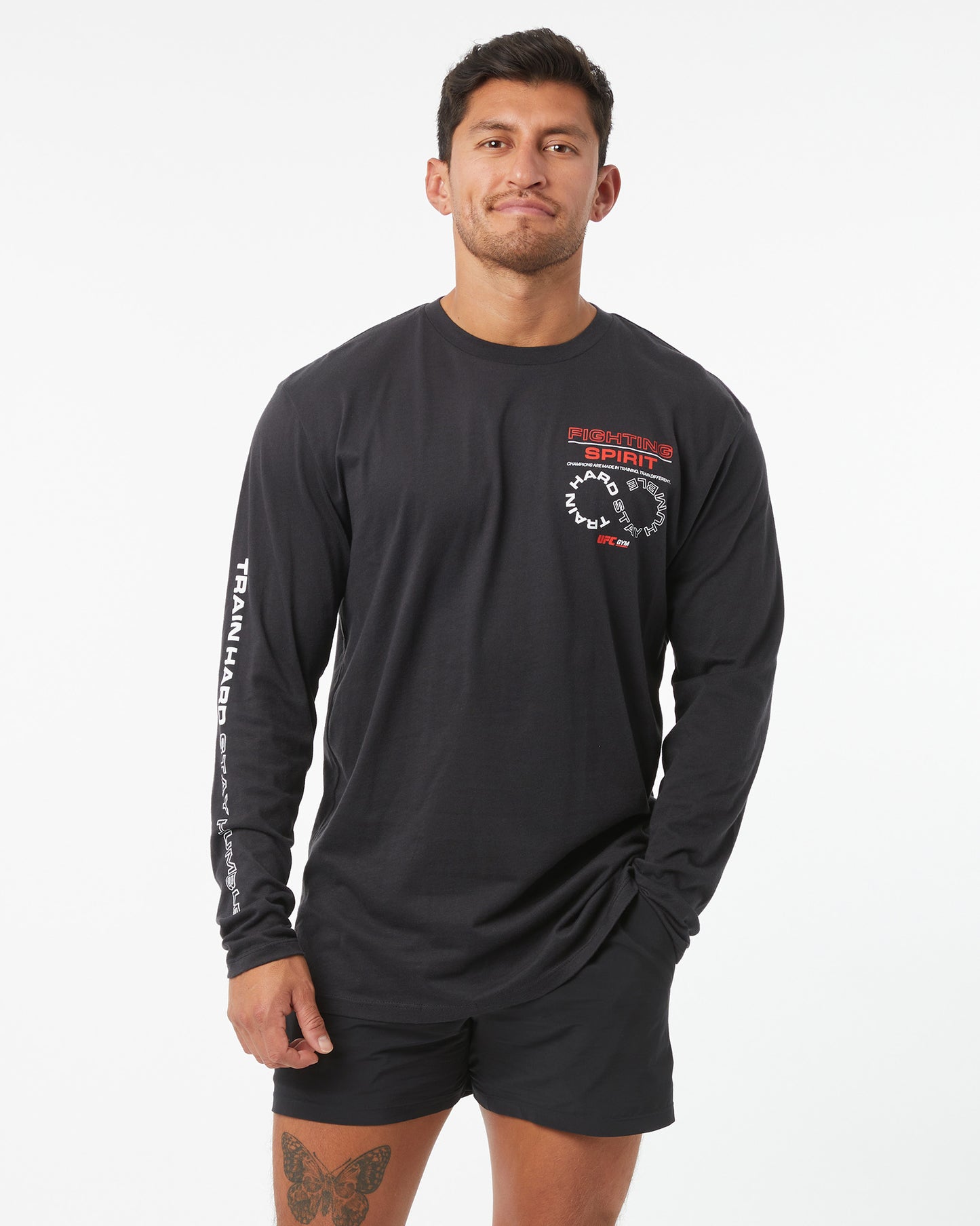 Man wearing a black long-sleeve athletic shirt with a logo on a white background