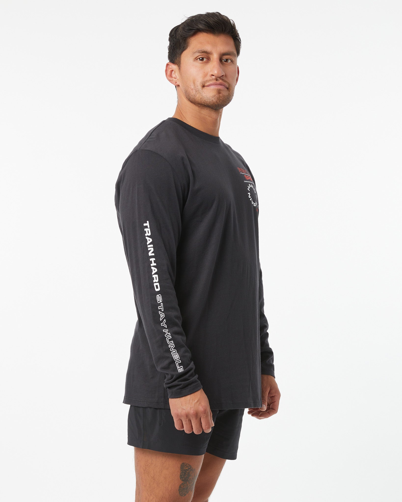 Man wearing a black long-sleeve athletic shirt with text on sleeves against a white background