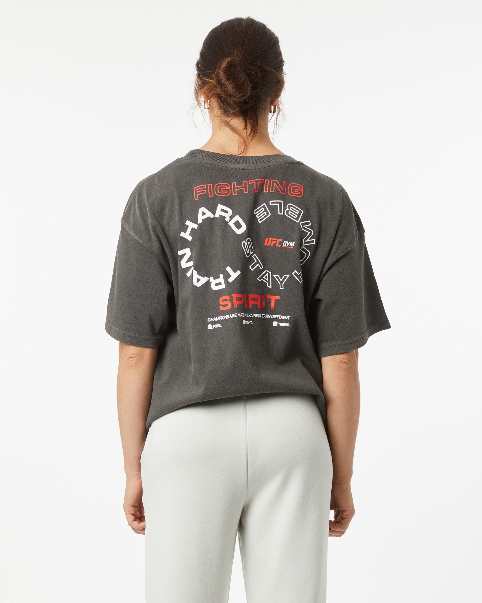 Person wearing a dark gray t-shirt with red and white text on the back, standing against a white background.