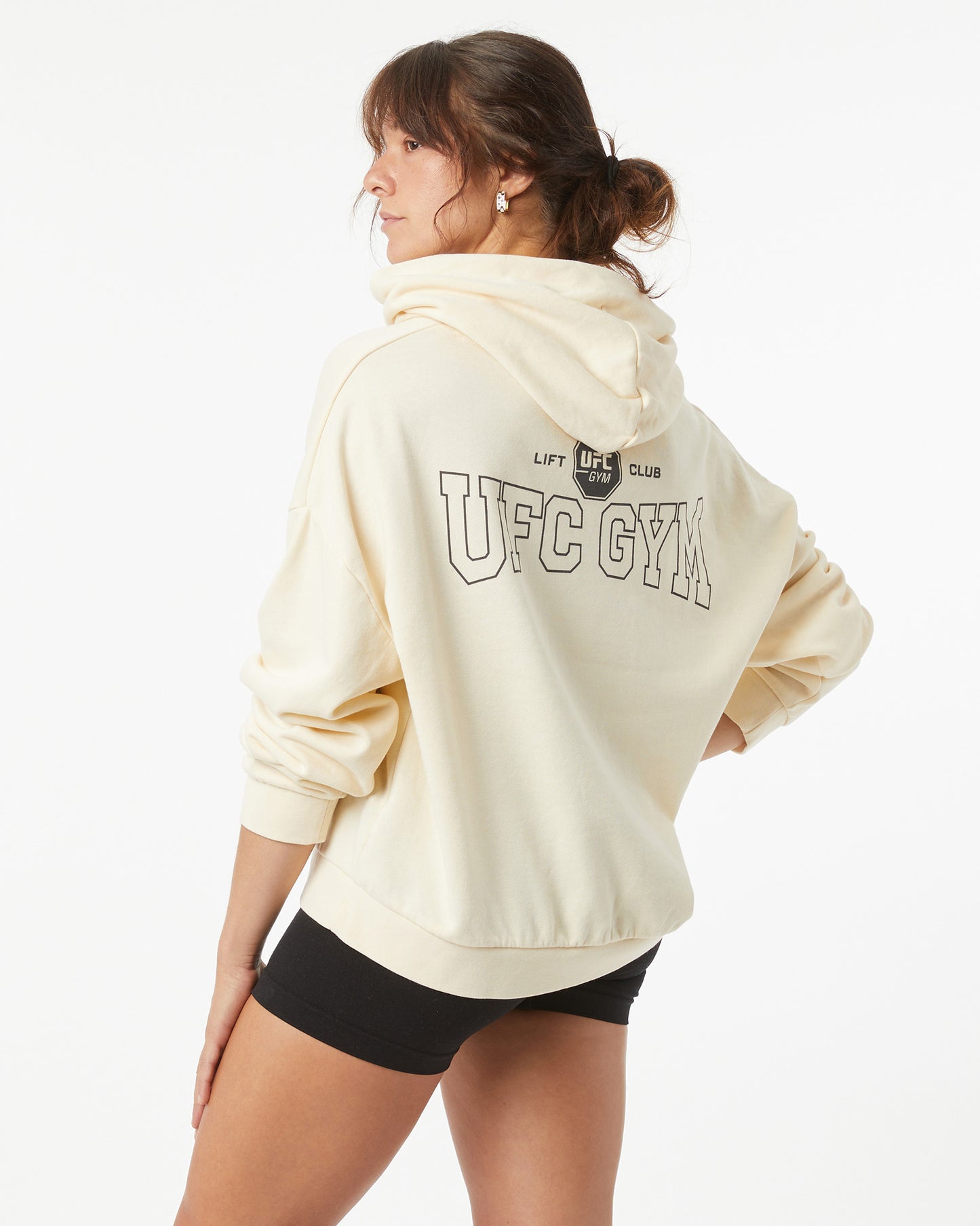 Woman wearing a bone white UFC Gym hoodie on a white background