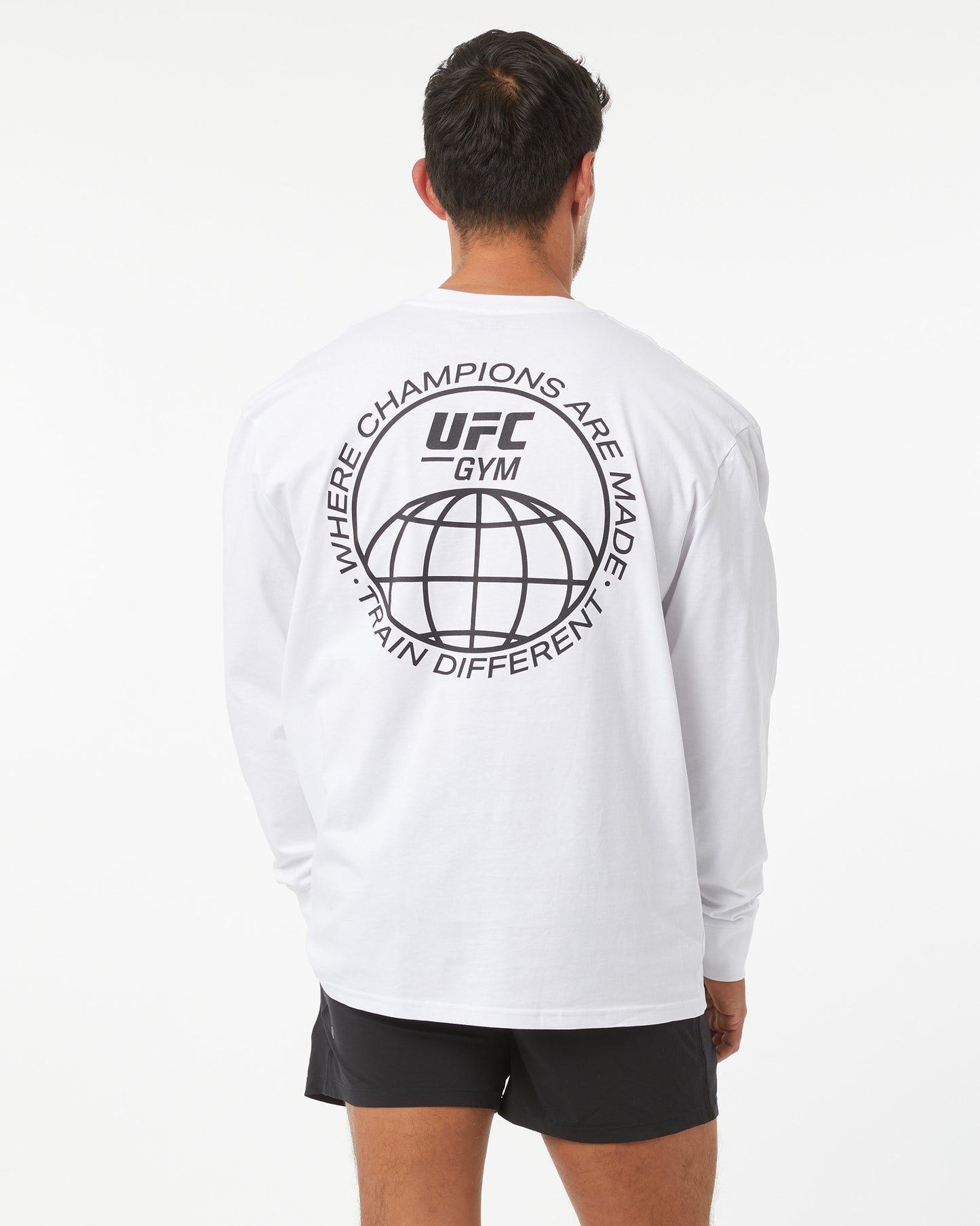 Person wearing a white UFC Gym long-sleeve shirt with a logo on the back.