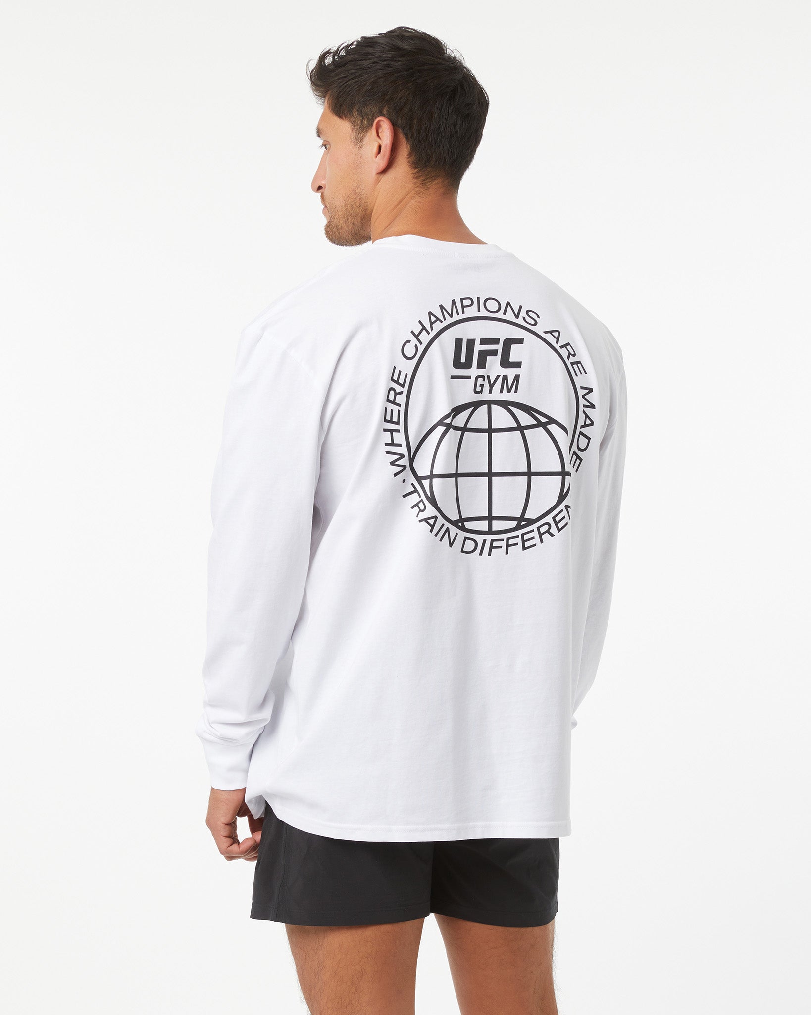 Person wearing a white UFC Gym long-sleeve shirt with branding on the back.