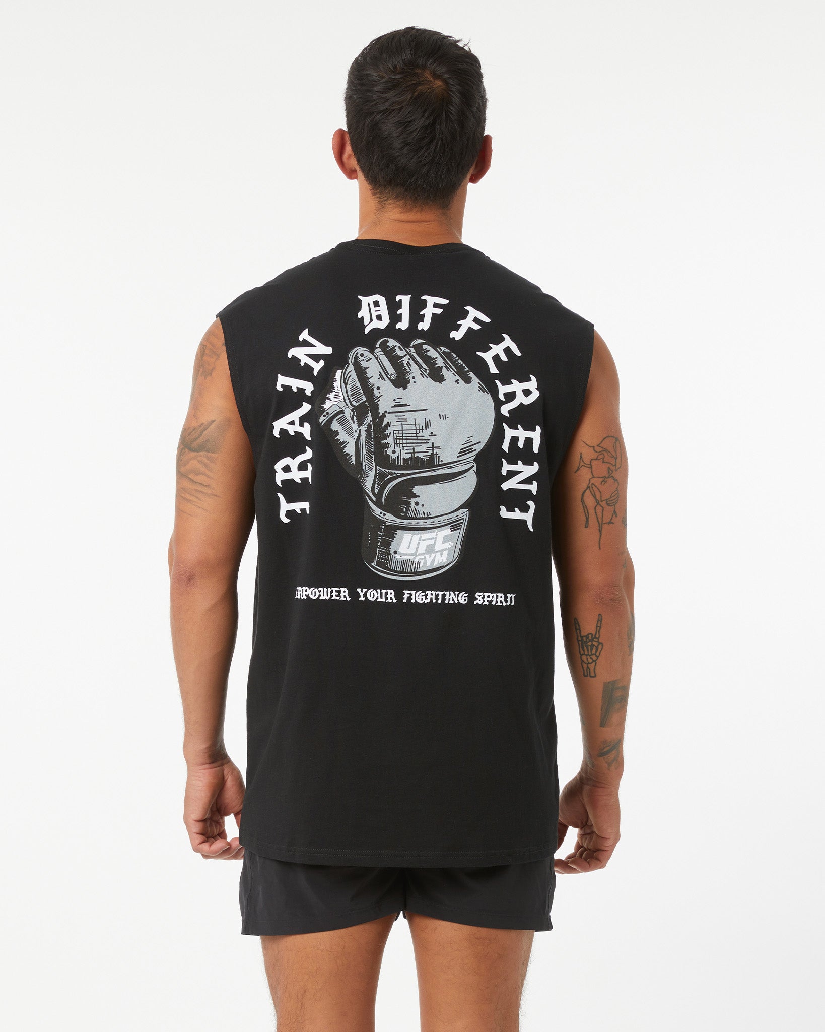 Person wearing a black sleeveless shirt with a graphic and text on the back, standing against a white background.