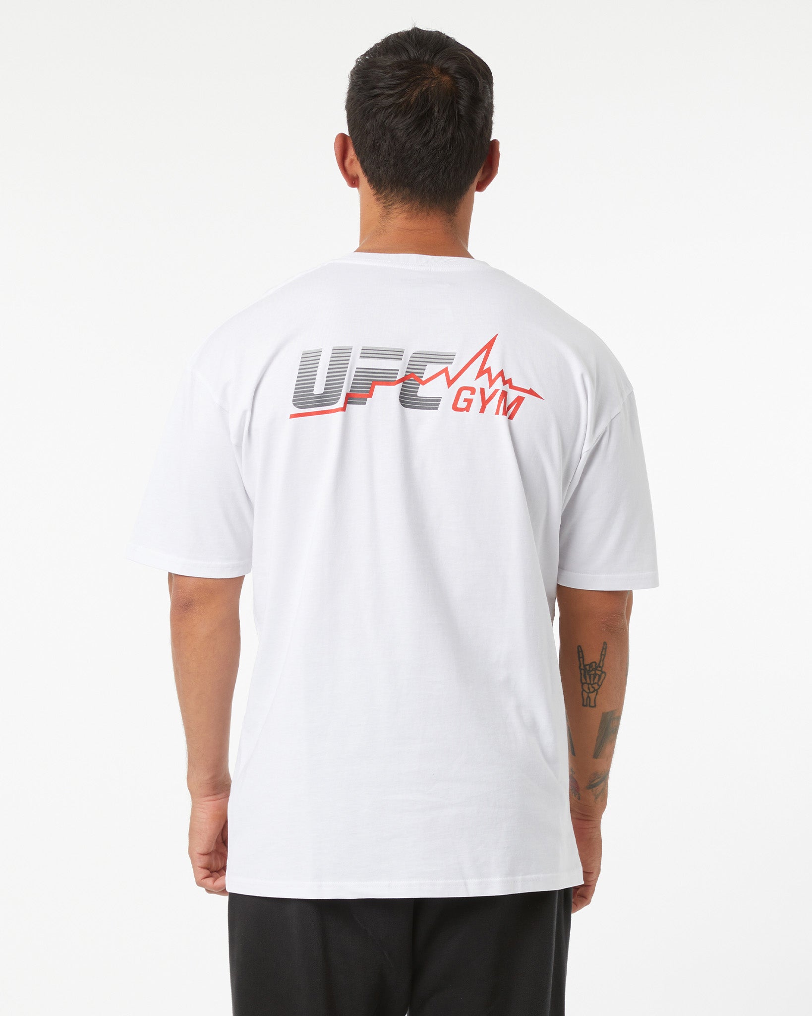 Person wearing a white UFC Gym t-shirt with branding on the back against a white background