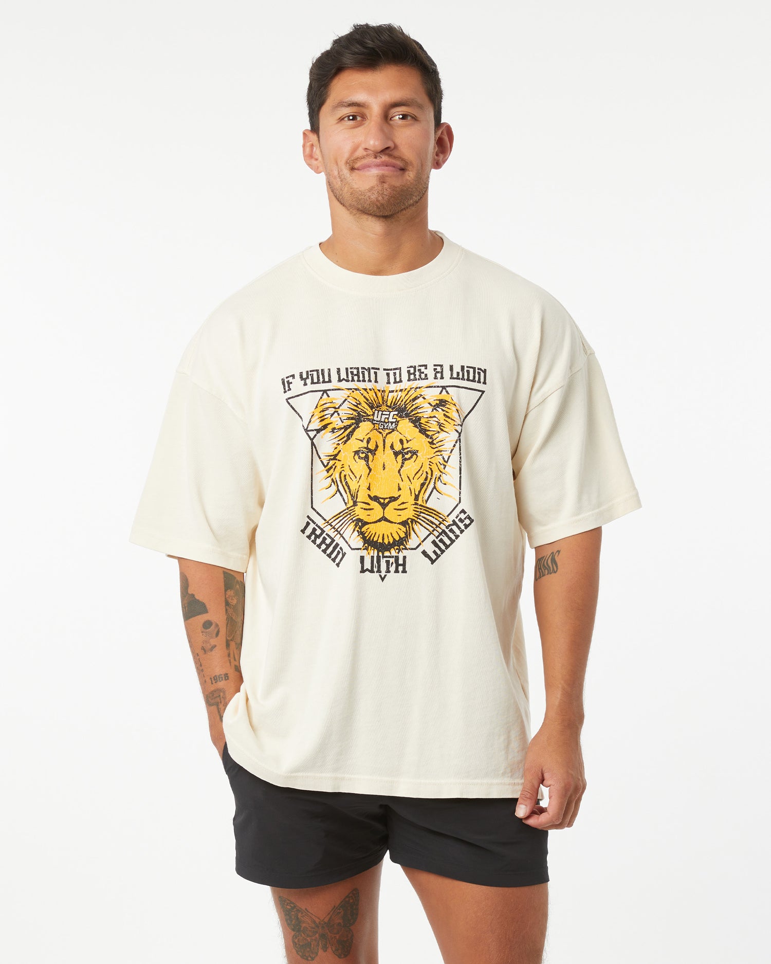 Man wearing a cream t-shirt with a lion graphic and text on a white background