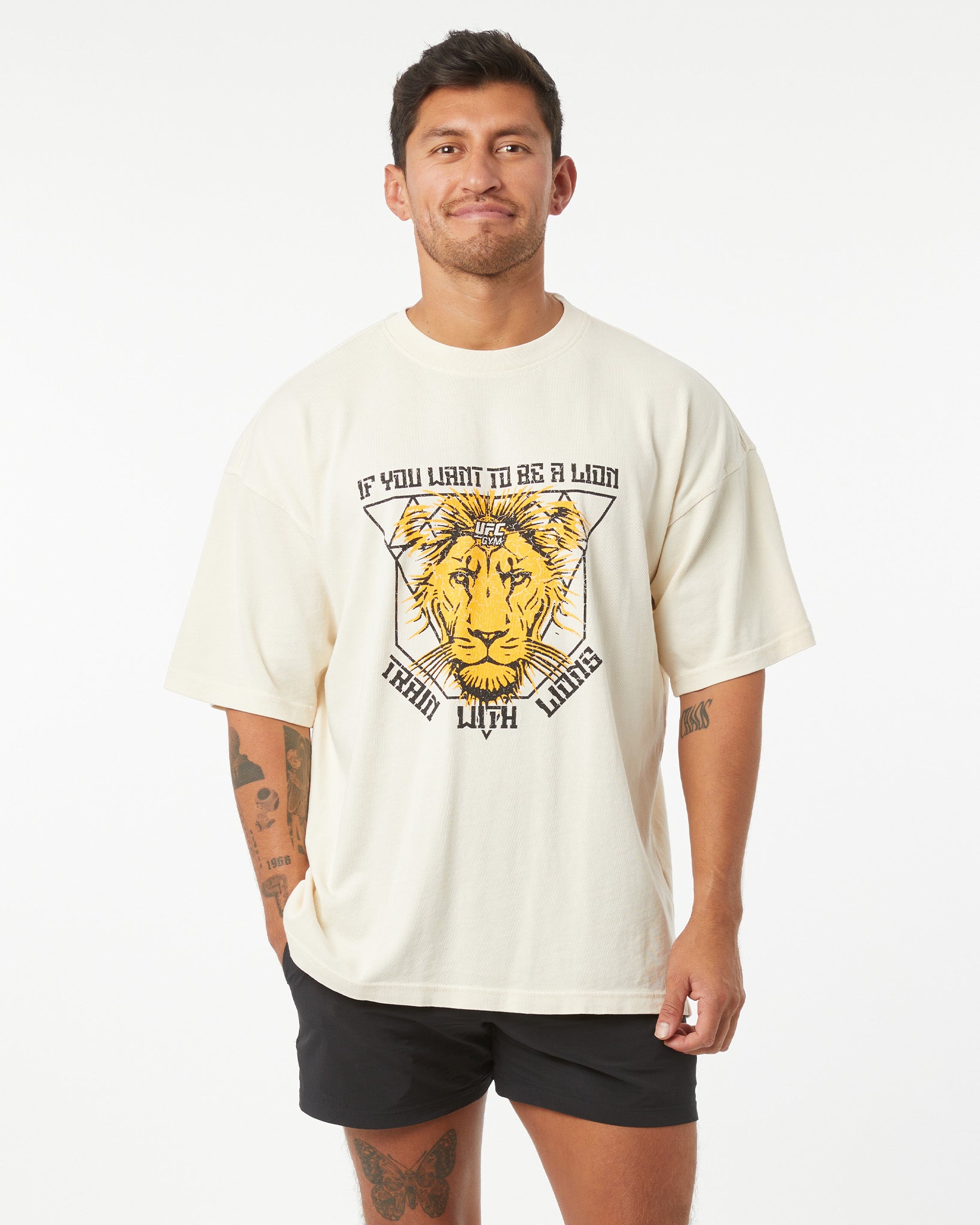 Man wearing a cream t-shirt with a lion graphic and text on a white background