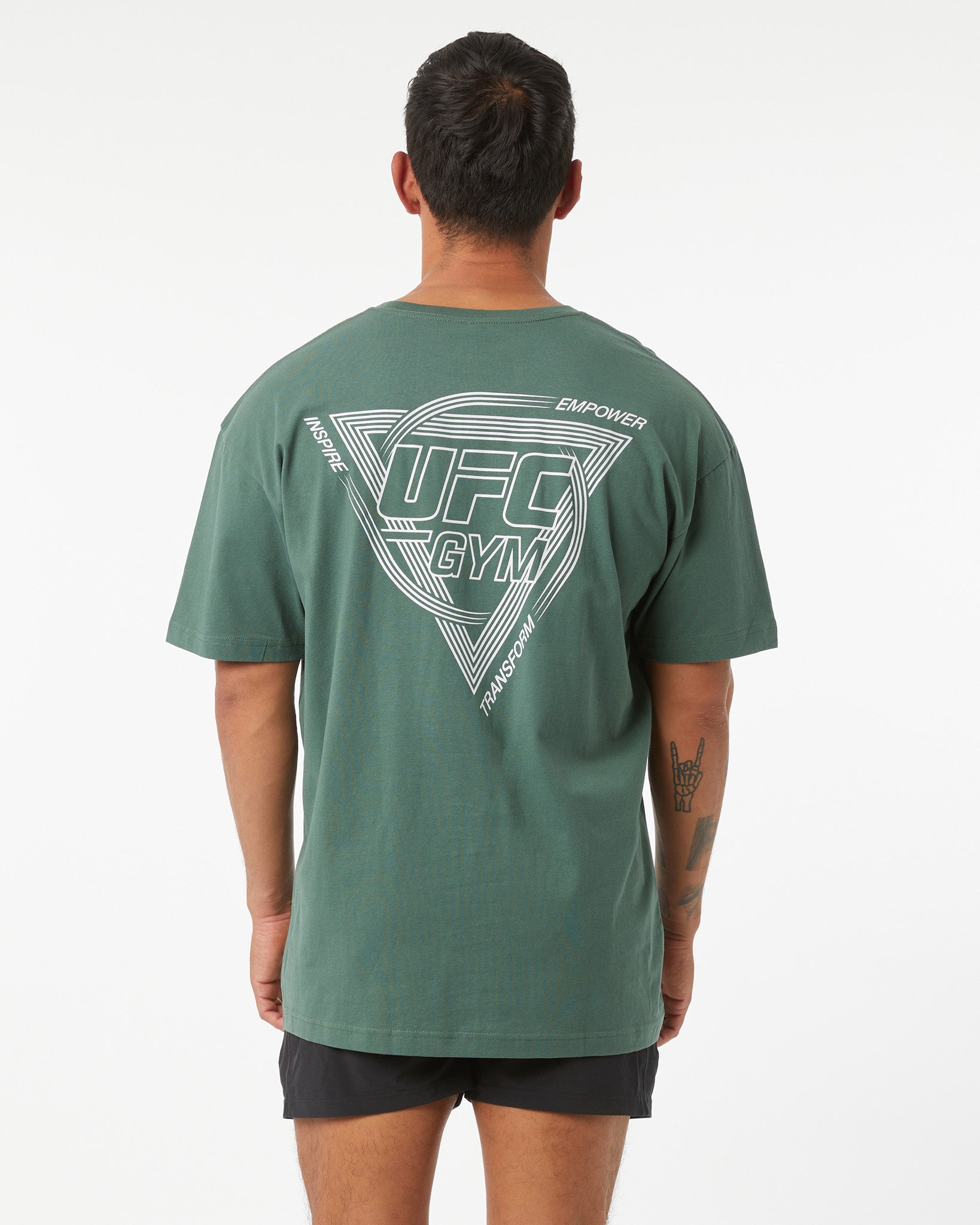 Person wearing a green UFC Gym t-shirt with branding on the back against a white background