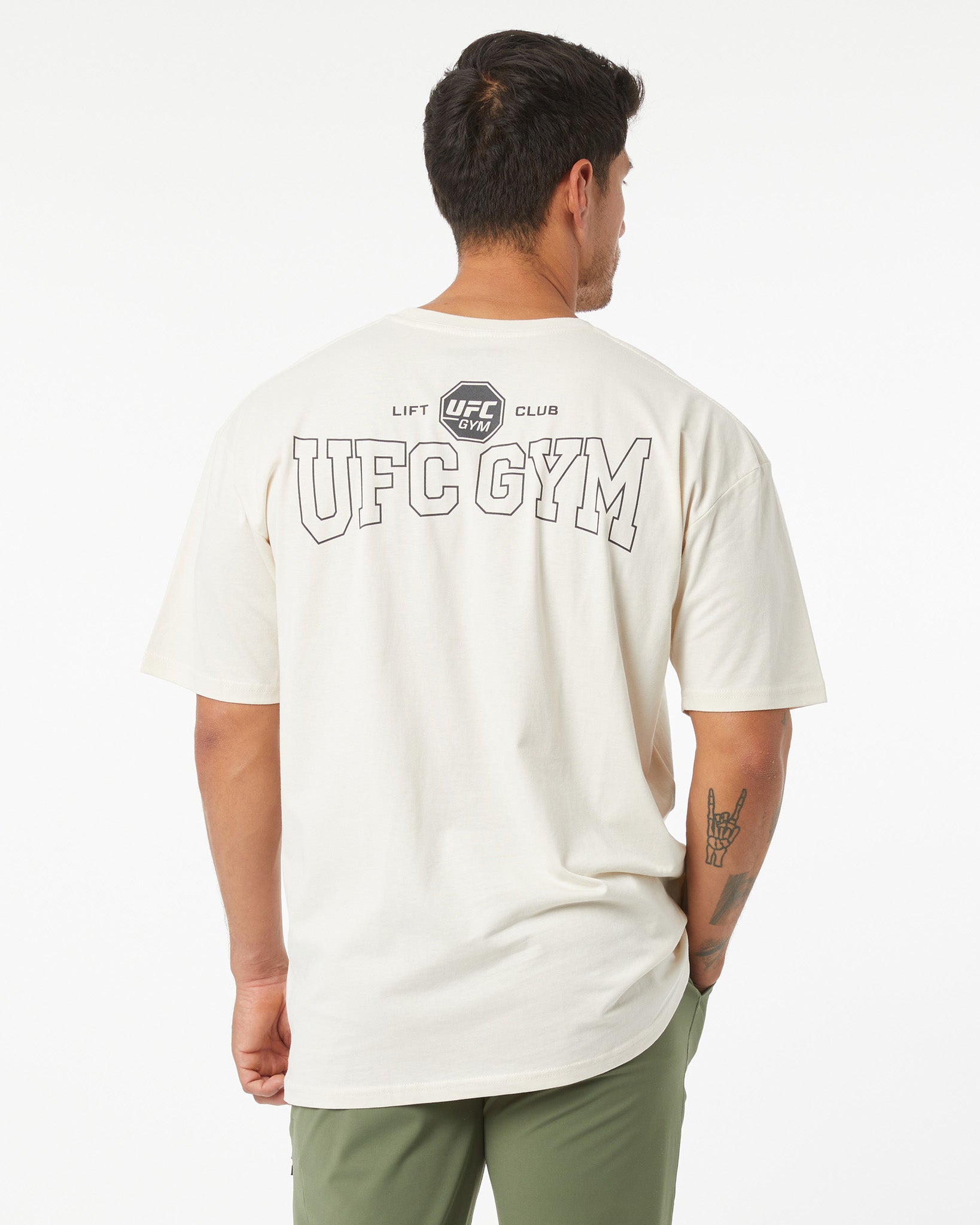 Person wearing a white UFC Gym t-shirt with branding on the back against a white background