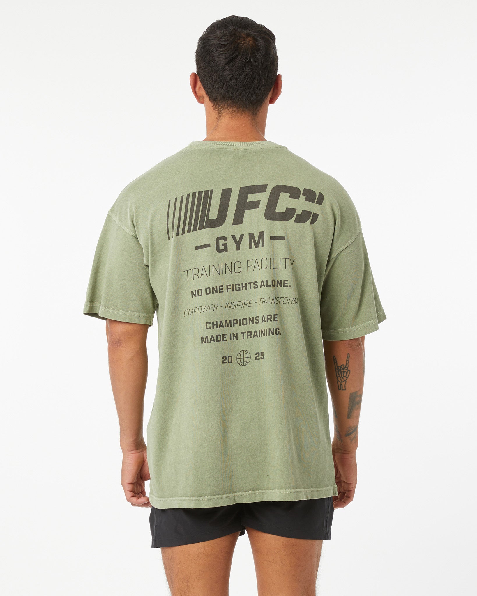 Person wearing a green UFC Gym t-shirt with text on the back against a white background