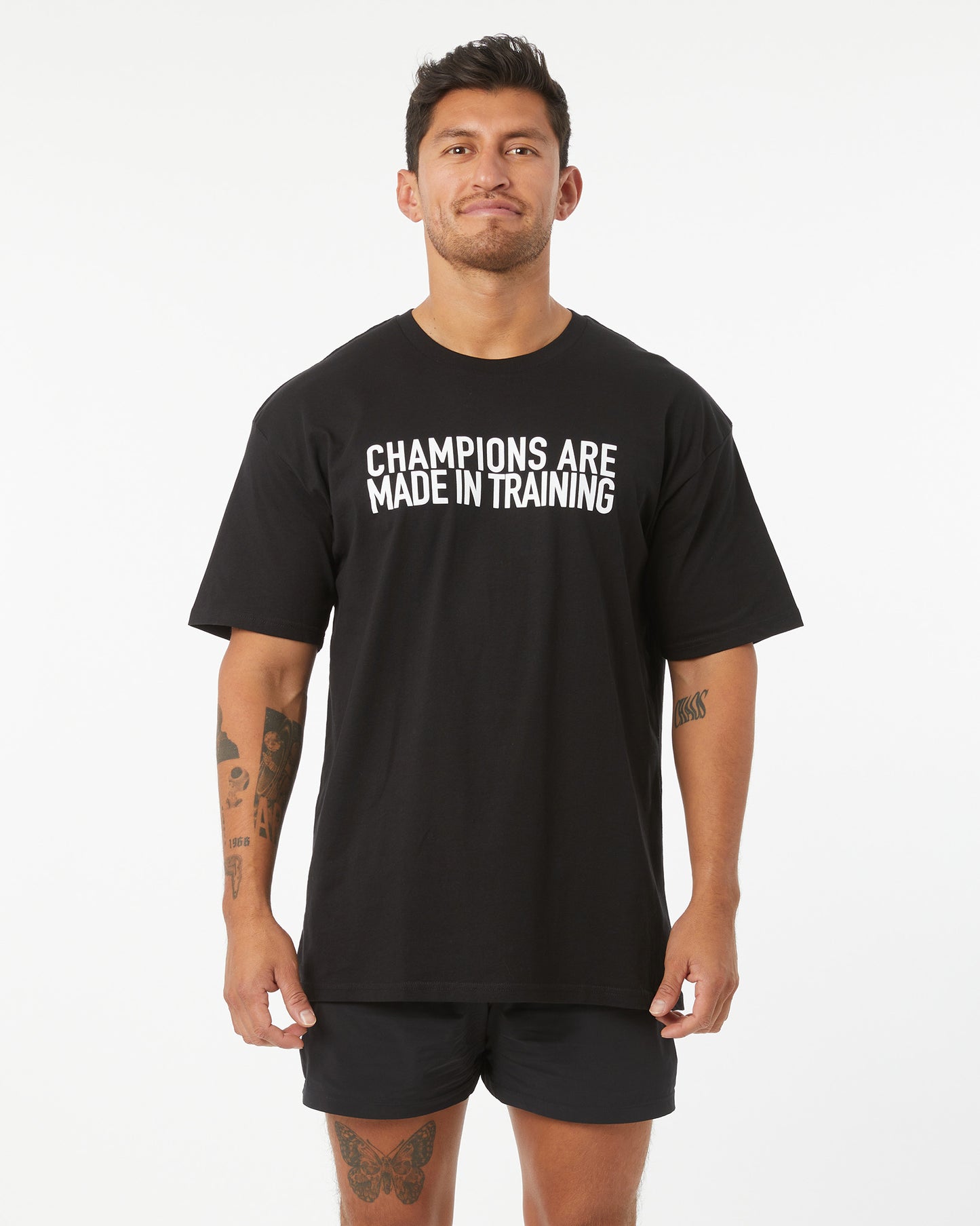 Man wearing a black t-shirt with 'Champions are made in training' text on a white background