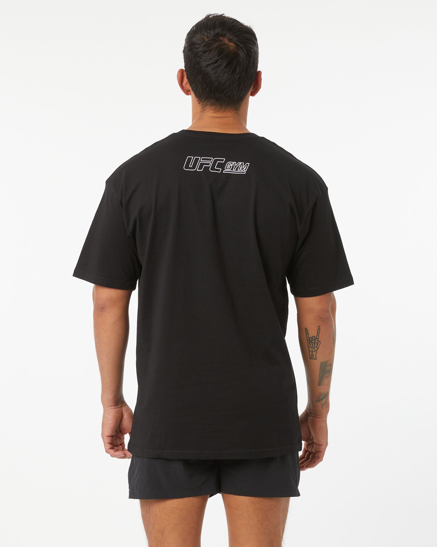 Person wearing a black UFC t-shirt with logo on the back against a white background