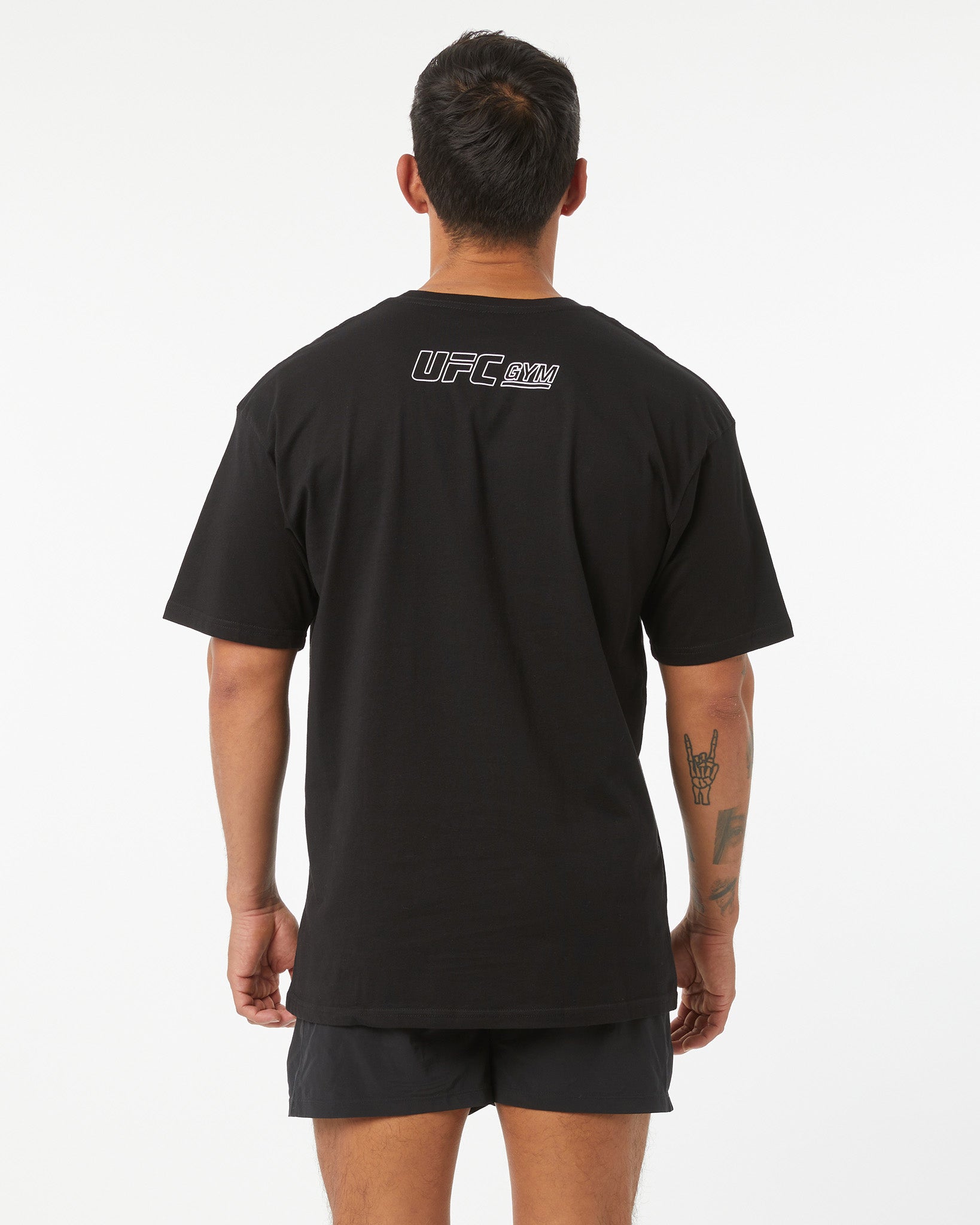 Person wearing a black UFC t-shirt with logo on the back against a white background